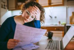 Woman looking at bill with hand on forehead